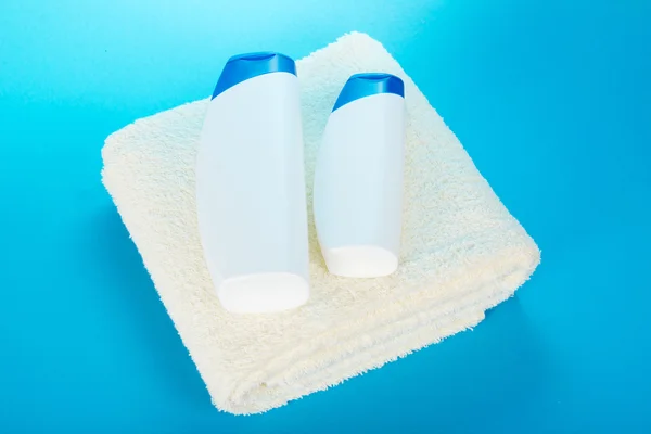 Xampu e gel em uma toalha, em um fundo azul — Fotografia de Stock