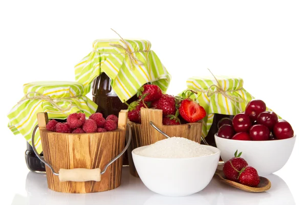 Jam, raspberry and strawberry in buckets, sweet cherries and sugar in cups and berries in a spoon — Stock Photo, Image