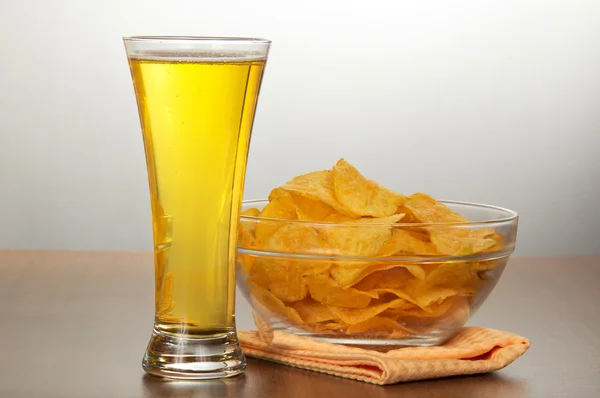 Glass of beer, bowl with chips and a napkin on a gray background — Stock Photo, Image