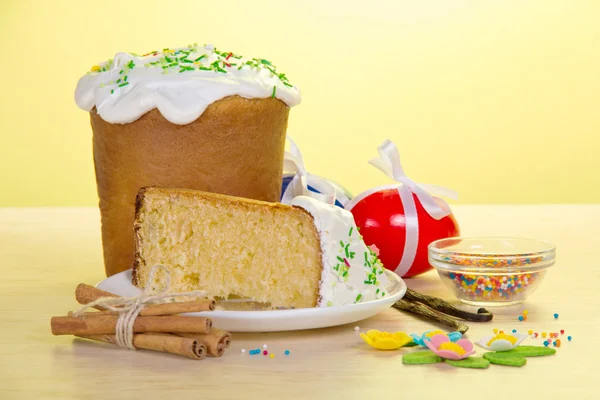 Piece of an cake on a saucer and eggs on a table, on a yellow background — Stock Photo, Image