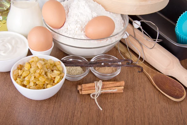 Mehl, Milch, saure Sahne und Eier, Rosinen, Sesam, Vanille und Zimt auf einem Tisch — Stockfoto