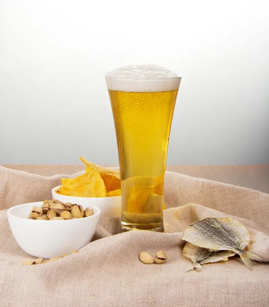 Sackcloth, glass of beer, pistachio, salty fish and fried potatoes — Stock Photo, Image