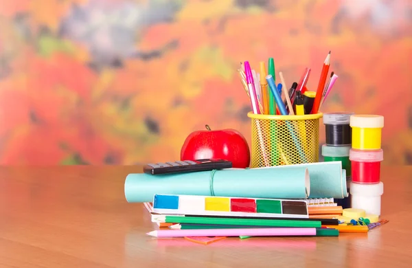 Writing materials, calculator, paints and an apple — Stock Photo, Image