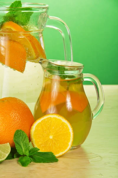 Gobelet avec boisson, un verre, une lime juteuse et des oranges — Photo