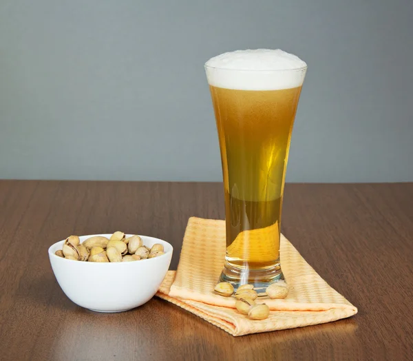 Verre de bière, bol aux pistaches et une serviette — Photo