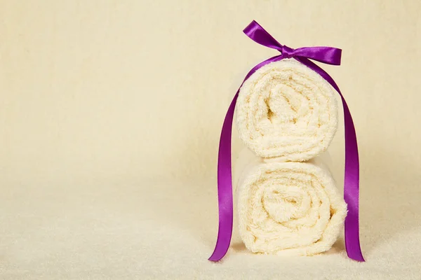 Dos toallas un rollo decorado con una cinta contra un paño de rizo —  Fotos de Stock