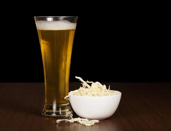 Verre de bière et calmars salés dans un bol, sur la table — Photo