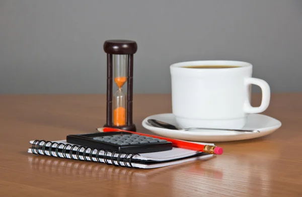 Leere Seiten für Notizen, Bleistift, Taschenrechner, Tasse Kaffee, Untertasse, Löffel und Sanduhr — Stockfoto