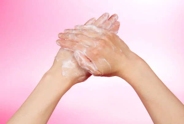 Vrouw handen in sopje, op een roze achtergrond — Stockfoto