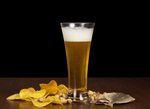Golden chips, pistachios, salty fish and beer glasson the table — Stock Photo, Image