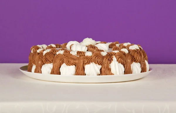 Mor bir arka plan üzerinde beyaz bir bez üzerinde bir pasta ile çanak — Stok fotoğraf