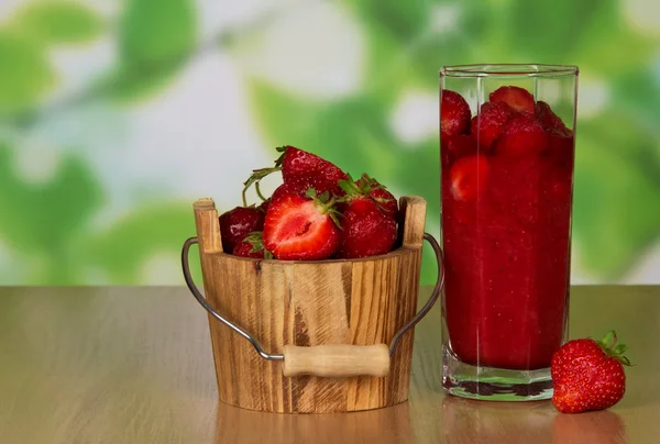 Jahody v dřevěné vědro, ve sklenici, berry v blízkosti na stůl — Stock fotografie