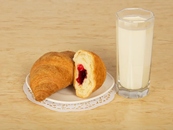 Croissant op een schotel en een glas melk, op een tafel — Stockfoto
