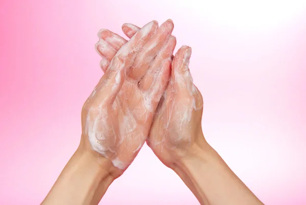 Mousse de savon sur les mains féminines, sur fond rose — Photo