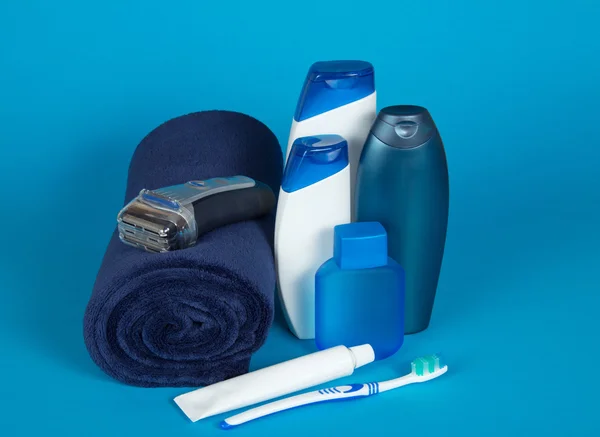 Toalla, maquinilla de afeitar, cosméticos, cepillo de dientes y pasta sobre un fondo azul —  Fotos de Stock
