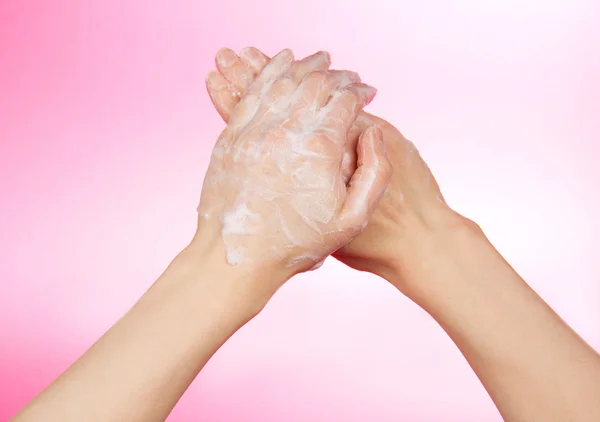 Mani di donna in sapone, su sfondo rosa — Foto Stock