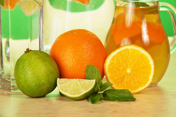 Gobelet avec boisson, un verre, une lime juteuse et des oranges — Photo