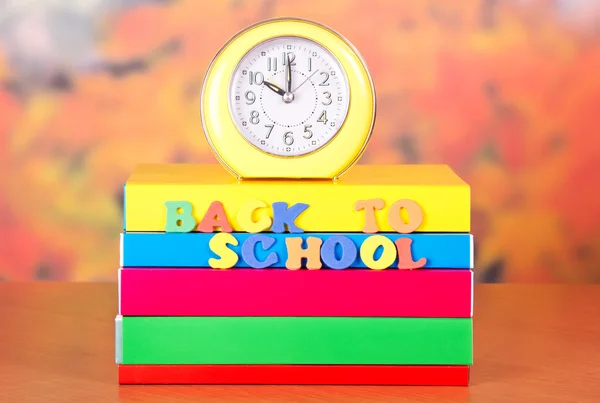 Stapel van schoolboeken en wekker op een tafel — Stockfoto