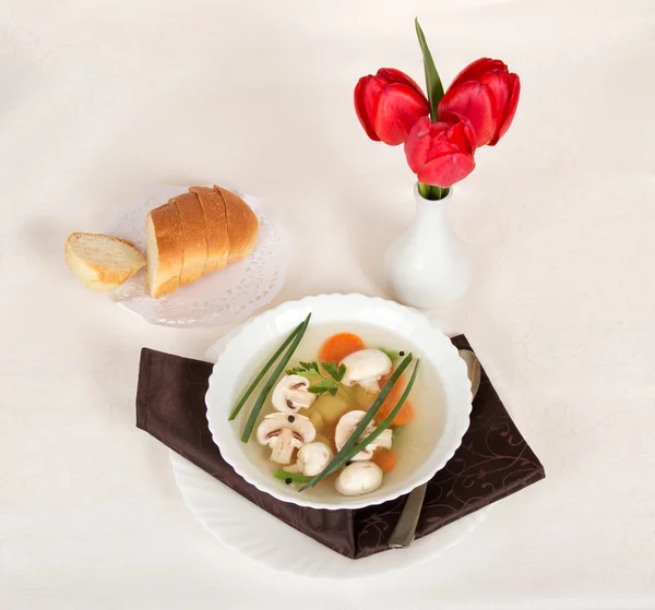 Pilzsuppe, Brotscheiben und Tulpen in einer Vase auf weißem Tuch — Stockfoto