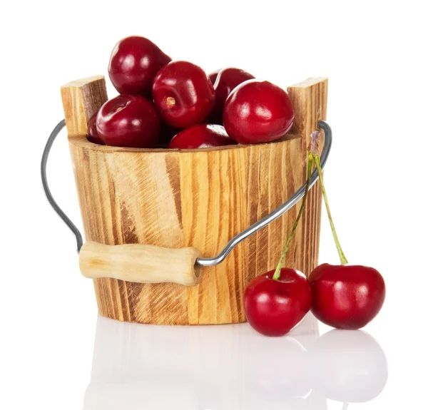 Sweet cherries in a wooden bucket and two berries near — Stock Photo, Image
