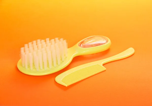 Children's brush and hairbrush on an orange background — Stock Photo, Image