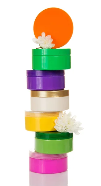 Stapel potten van verschillende cosmetische crème en bloem geïsoleerd op whit — Stockfoto