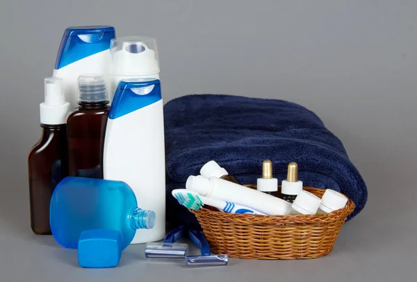 Set voor scheren, shampoo, douchegel en een handdoek zwemwater op een grijze achtergrond — Stockfoto