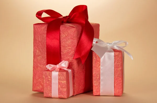 Drei Geschenkboxen mit Schleife und Schleife, auf beigem Hintergrund — Stockfoto