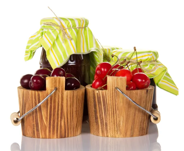 Sweet cherries in buckets, and two banks with the ready jam — Stock Photo, Image