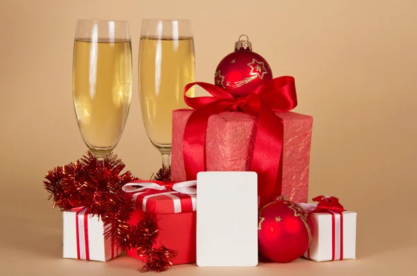 De giften van Kerstmis speelgoed, klatergoud, champagne en lege kaart, op een beige achtergrond — Stockfoto