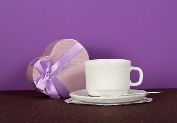 Set of tea-things and souvenir heart on a brown cloth, on a violet background