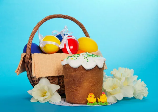 Easter cake, marzipans, flowers and basket with eggs, on a blue background — Stock Photo, Image