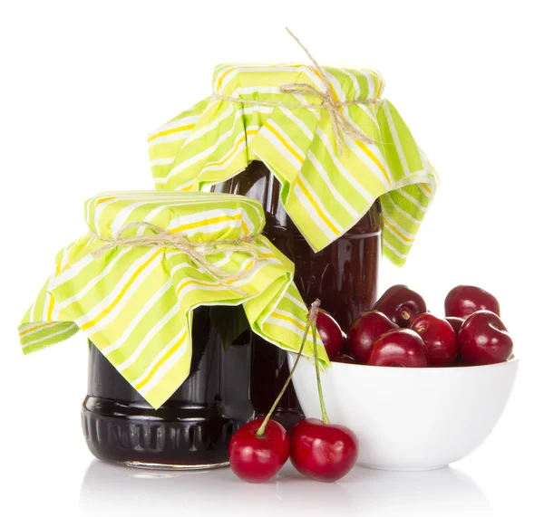 Two jars of jam, a cup with sweet cherries, isolated on white — Stock Photo, Image