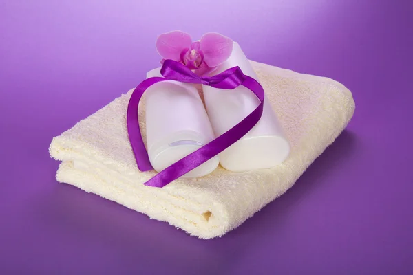 Towel and set for the bathing, decorated with a ribbon and an orchid flower on the violet — Stock Photo, Image