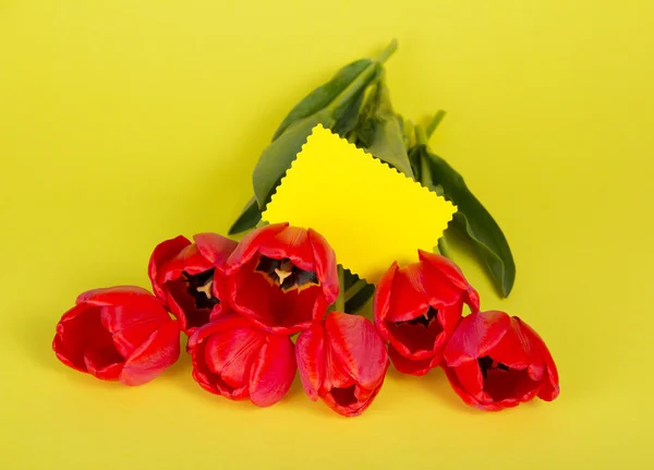 Букет красных тюльпанов и пустая карточка для сообщения — стоковое фото