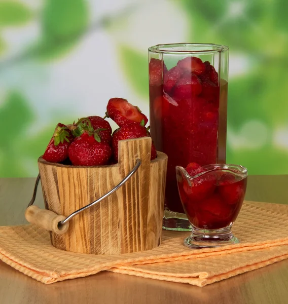 Jahody v kýblu a sklenici, plody v misce a ubrousky na stůl — Stock fotografie