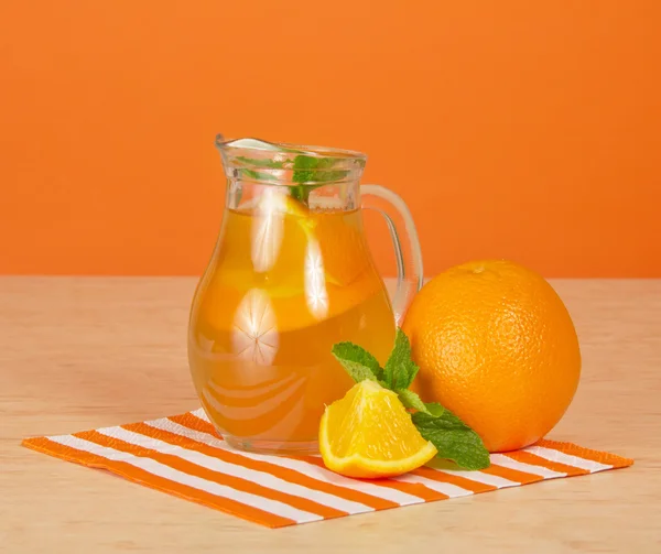 Cruche avec boisson, oranges mûres, une serviette rayée sur une table — Photo