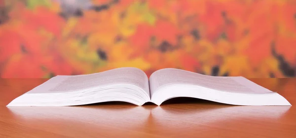 The open book on a table, against autumn leaves — Stock Photo, Image