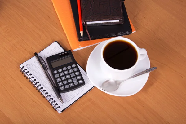 Bloc de notas, organizador, hojas vacías para notas, cuaderno de ejercicios un lápiz, la manija, la calculadora, taza de café en una mesa —  Fotos de Stock