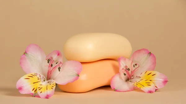 Set of toilet soap and the flower of an alstroemeria on a beige background — Stock Photo, Image