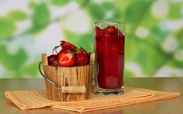 Dřevěné vědro s jahody, sklenici s jahodovou a ubrousky na stůl — Stock fotografie