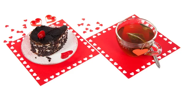 Шоколадный торт и горячий чай на красной салфетке с сердечками, изолированными на белом — стоковое фото