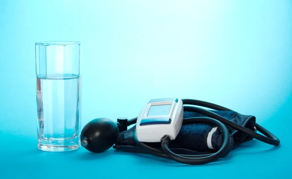 Das Gerät zur Messung des Drucks und ein Glas mit Wasser auf der blauen — Stockfoto