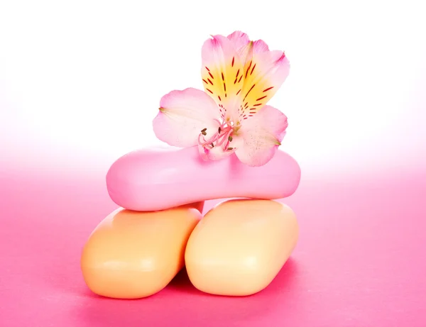 Diferentes pedaços de sabão e a flor em um fundo rosa — Fotografia de Stock
