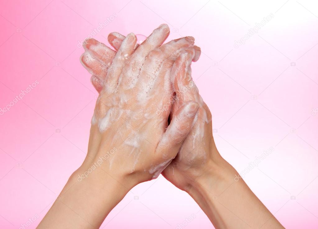 Woman washes her hands on a pink background