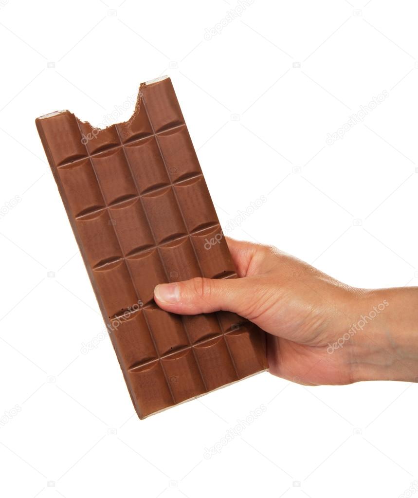 Female hand with a tile of milk chocolate where the slice is bitten off