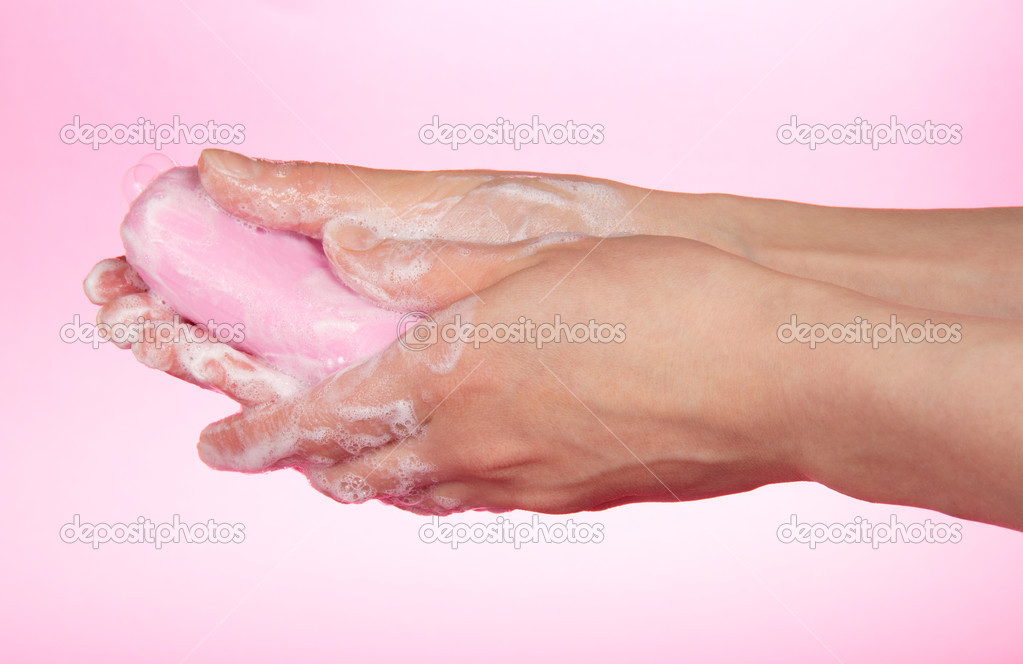 The woman washes hands about the soap on a pink background