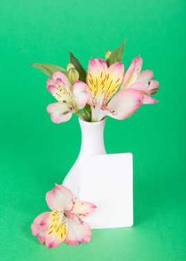 çiçek alstroemeria ve yeşil bir arka plan üzerinde bir vazo yakın boş oyun kağıdı