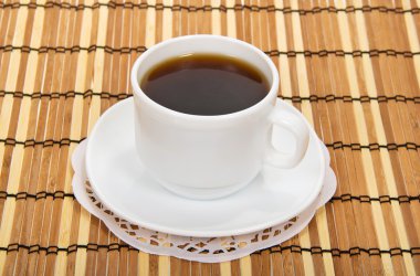 kopje koffie met een schotel tegen een bamboe servet