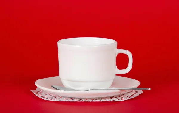 Saucer and cup on a napkin, against a red — Stock Photo, Image